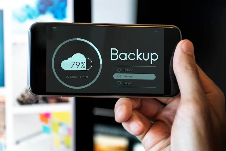 A hand holds a smartphone displaying a cloud backup status: 79% complete, with options to upload, view recent files, and share.