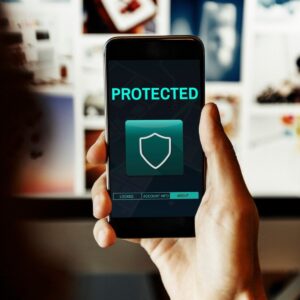 A person holds a smartphone displaying a PROTECTED screen with a shield icon, indicating security features in a digital space.