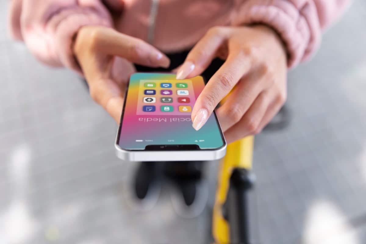A person holding a smartphone displaying a colorful app interface, with icons for social media and apps, in an outdoor setting.