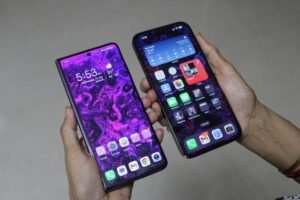 Two smartphones held side by side, featuring vibrant abstract wallpapers and app icons, displaying time and weather information.