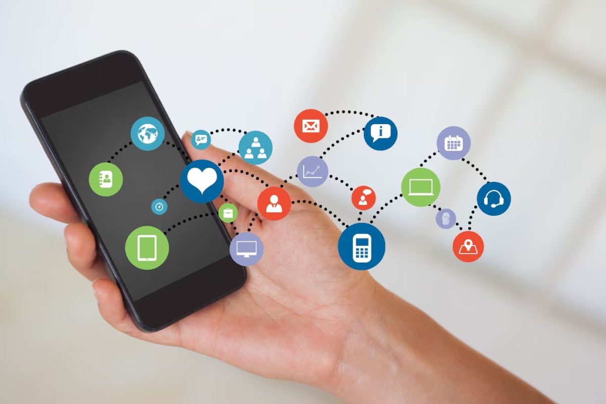 A person holding a smartphone with colorful app icons and connections symbolizing communication and technology around it.