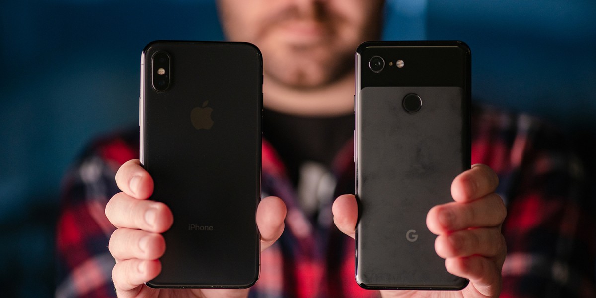 A person holds an iPhone and a Google Pixel smartphone, showcasing the back views of both devices against a blurred blue background.