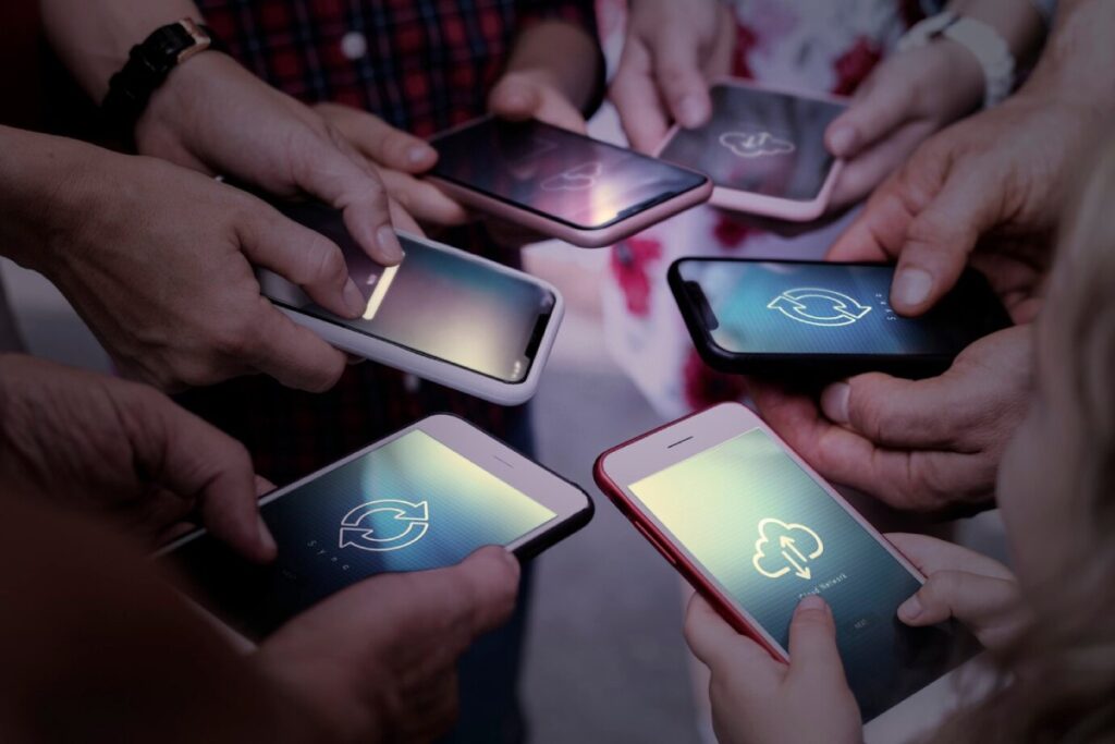 Several hands holding smartphones with sync and cloud icons displayed on their screens, symbolizing data sharing and connectivity.