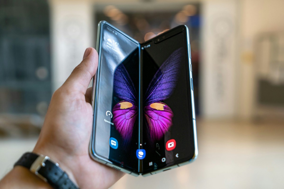 A person holds a Samsung Galaxy Z Fold phone, opened to display vibrant butterfly graphics on its large, flexible screen.